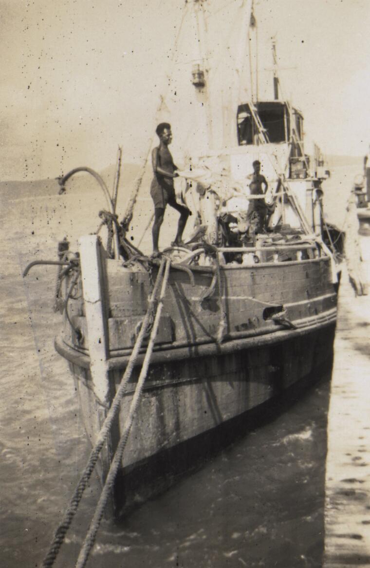 Two unidentified men standing on the boat, Thursday Island, Engineers Wharf, 1956