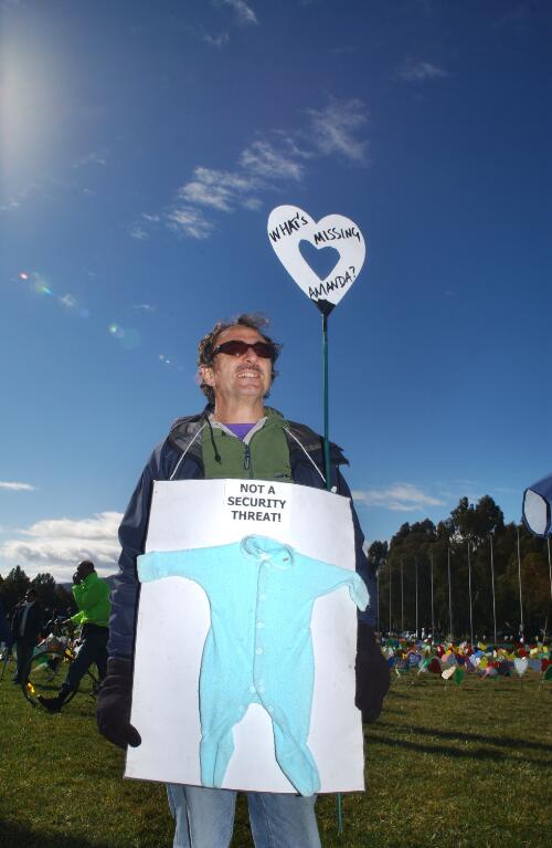 [Male demonstrator carrying placard featuring baby's jumpsuit at United Nations World Refugee Day and Field of Hearts event, Canberra, 20 June 2004] [picture] / Loui Seselja