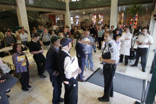 [Police Officer talking to members of the public who are locked in the foyer of the National Library of Australia in response to the delivery of suspicious mail, 6 May 2005] [picture] / Damian McDonald