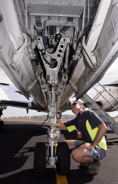 Darren Wintour, Engineer, inspects the undercarriage of  MacAir Airlines' SAAB 340 VH-UYC 'Gurambilbarra' following arrival at Townsville International Airport, Townsville, Queensland, 30 May 2005 [picture] / Loui Seselja