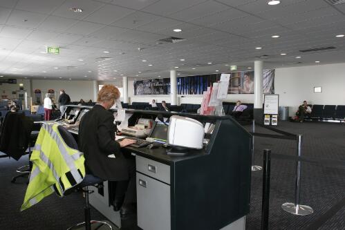 An unidentified Qantas employee working behind the Cityflyer service desk inside the Canberra Airport passenger terminal departure lounge, 8 June 2005 [picture] / Loui Seselja