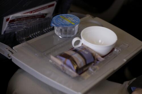 Inflight refreshment consisting of a chocolate brownie, tea or coffee, and water, Qantaslink's De Havilland Canada DHC-8-315 Dash 8, VH-TQM, flight QF 1414 from Canberra to Sydney,13 June 2005 [picture] / Loui Seselja