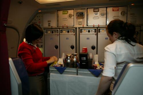 Flight attendants in the galley loading food and refreshments onto a catering trolley on board Virgin Blue's Boeing 737-800 "Virginia Blue", VH-VUA, 21 June 2005 [2] [picture] / Damian McDonald