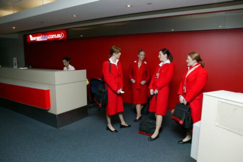 Virgin Blue flight attendants in uniforms featuring red overcoats and scarves, in the domestic departure terminal at Tullamarine Airport, Melbourne, 21 June 2005 [2] picture] / Damian McDonald