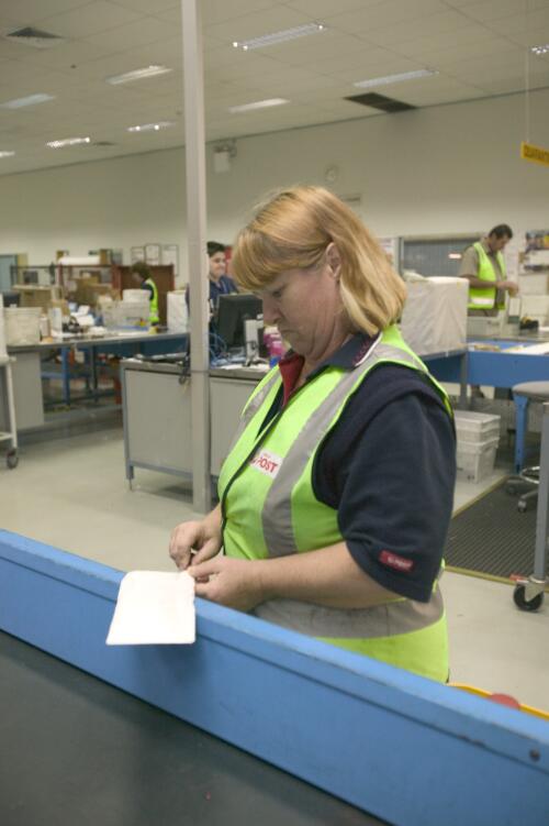 Australian Quarantine and Inspection Service officer, Sue Beattie, opening a letter that 'Wayne' the detector dog has identified as suspicious, Australian Quarantine and Inspection Service mail room, Brisbane Airport, 29 June 2005 [picture] / Greg Power