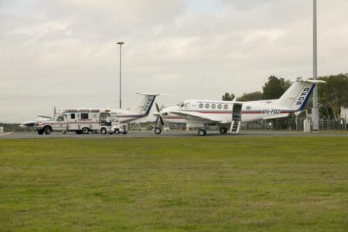 Royal Flying Doctor Service of Australia Beechcraft aeroplanes and a Queensland Ambulance Service ambulance parked on the apron, Brisbane Airport, 1 July 2005 [picture] / Greg Power