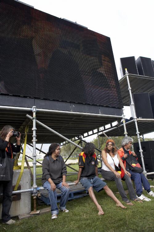 Prime Minister Kevin Rudd on a big screen television, with four people sitting on the scaffolding and a photographer to the left, during the Apology to the Stolen Generations at Parliament House, Canberra, 13 February 2008 [picture] / Greg Power