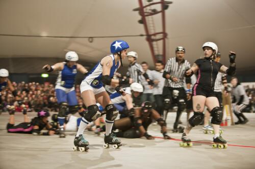 Victorian Roller Derby League All-Stars jammer Kittie von Krusher skating past a group of fallen skaters, Melbourne Showgrounds, Melbourne 23 July 2011 [picture] / Samuel Cooper