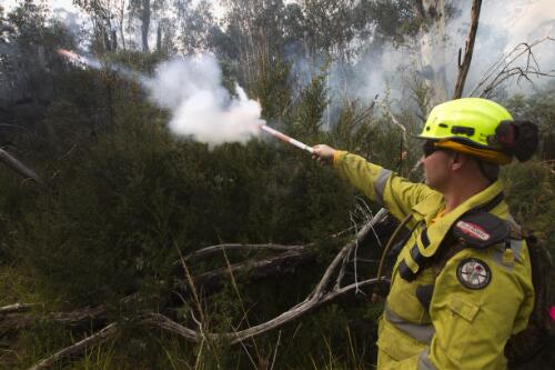 ACT Parks and Conservation Service fire fighter shoots an Easy Strike self propelled incendiary flare into the bush during a controlled burn within Namadgi National Park, Australian Capital Territory, April 2013, 2 / Lannon Harley