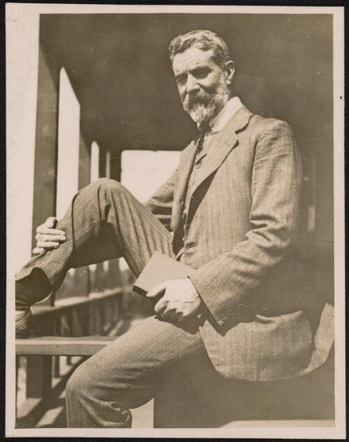 [Portrait of Alfred Deakin seated on a verandah holding a book] [picture]