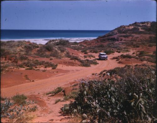 [Car on a red soil track near the coast, Western Australia] [transparency] / [Frank Hurley]