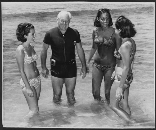 [Harold Holt in a wetsuit with three daughters-in-law in bikinis standing in the ocean] [picture]