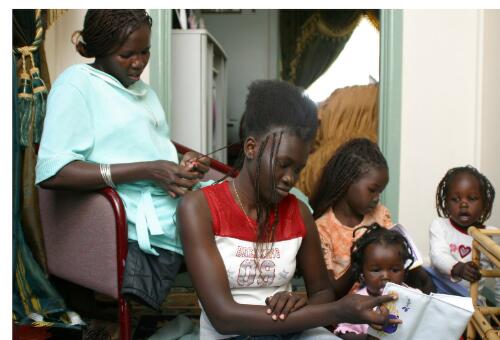 Jane Mabior plaits extensions into 19 year old cousin Regina Deng's hair whilst the girls look on, Melbourne, 2005 [picture] / June Orford
