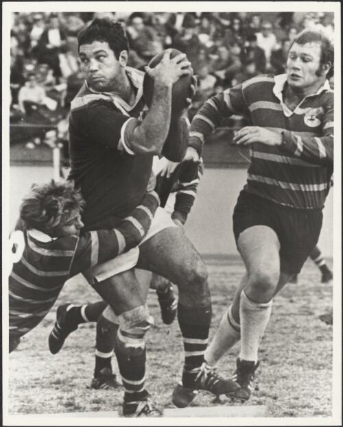 Rugby League player, Arthur Beetson, looks for a team mate before passing the ball [picture] / Ern McQuillan