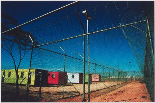 A row of accommodation buildings [behind a barbed wire fence at Woomera Detention Centre], 2005 [picture] / Dean Sewell