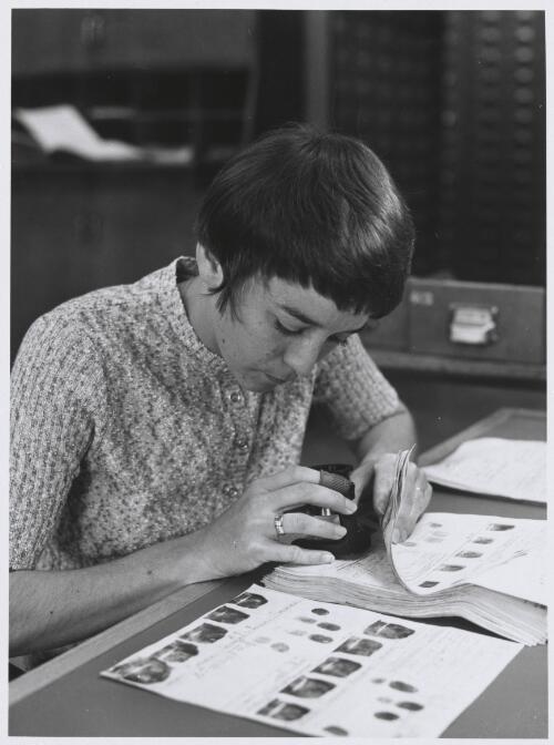 Australia's first woman trainee fingerprints expert, Constable Barbara Saunders at work matching fingerprints in the Criminal Investigation Branch at Melbourne's police headquarters,1972 [picture] / Don Edwards