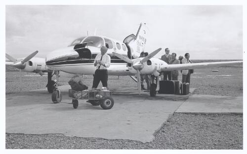 A twin engine plane with passengers and a staff member at  Coober Pedy airport, South Australia, 1970 [picture] / Jeff Carter