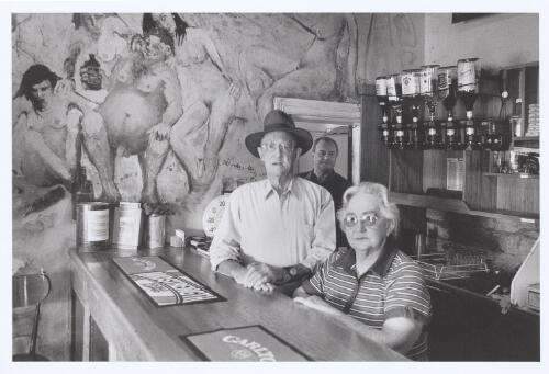 Former owners Barney and Josie Davey, with current  owner Peter Petrovitch, near Clifton Pugh mural in the bar of the Family Hotel, Tibooburra, 2005 [picture] / Jeff Carter