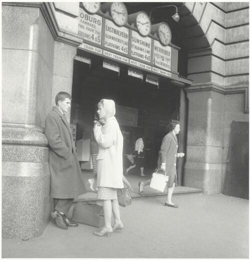 A man and woman meet under the clocks at Flinders Street Station, Melbourne, Victoria, ca.1957 [picture] / Jeff Carter