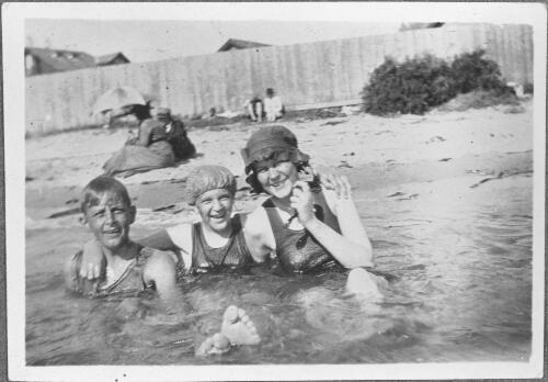Three young people sitting in shallow water at Brighton Beach, Melbourne, Victoria, ca. 1925 [picture]