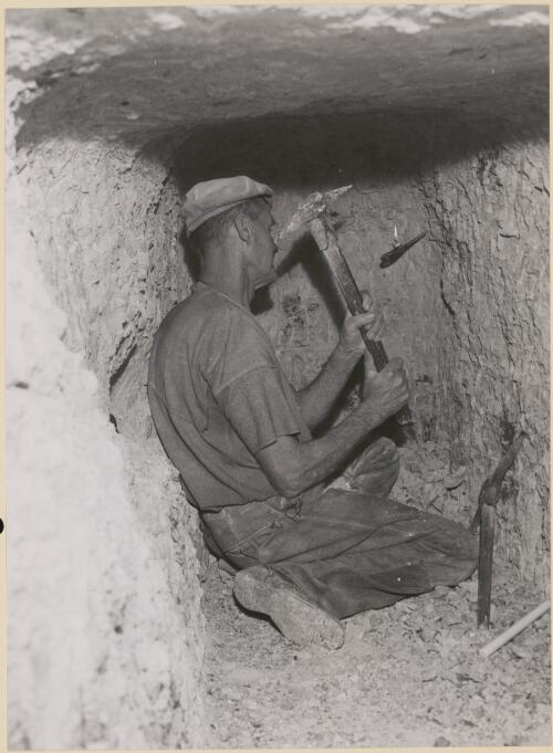 Opal miner, George Lowe chips away at the face of his opal mine, Lightning Ridge, 1953 [picture]