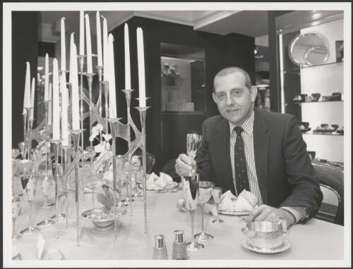 Portrait of Stuart Devlin, gold and silversmith, with a claret goblet, part of a gold and silver table setting made in his London workshop, 1985 [picture] / Australian Information Service Photograph by Eric Wadsworth