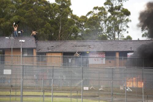 Detainees staging a demonstration from the roof of the Villawood Detention Centre while the buildings burn below, New South Wales, 17 November 2010 [picture] / Karl Sharp