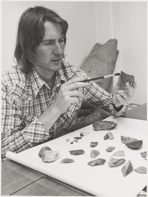 Kevin Kiernan cleaning stone tools recovered during an archaeological survey in the southwest wilderness of Tasmania, Hobart, Tasmania, 27 February 1981 [picture] / John McKinnon