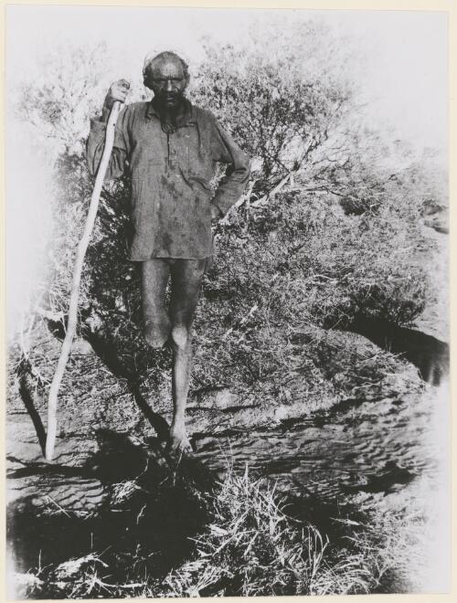 Aboriginal man of the Pintupi Language group leaning on a walking staff as he is missing his leg below the knee near Lake Mackay, Northern Territory, 1957 [picture] / Australian News and Information Bureau
