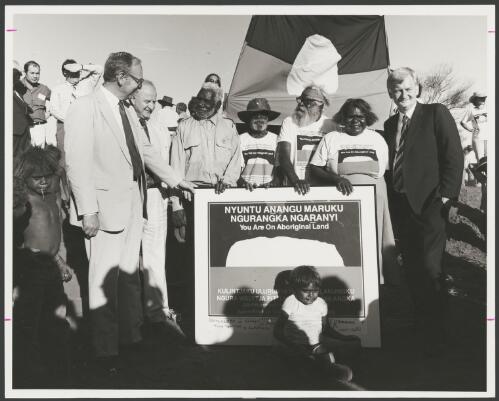 Sir Ninian Stephen, Clyde Holding MP, Mr Peter Bulla, Mr. Peter Kanari, Mr. Nipper Winmarti, Barbara Tjirkadu and Barry Cohen MP at the official ceremony of the handover of Uluru to its traditional owners, Northern Territory, 5 November 1985 [picture] / Department of Aboriginal Affairs