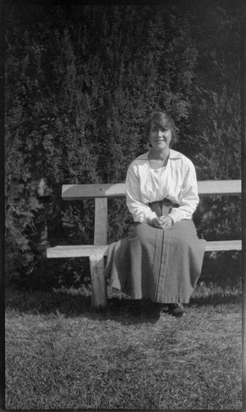 Young woman sitting on a garden bench, ca. 1910?, 2 [picture]