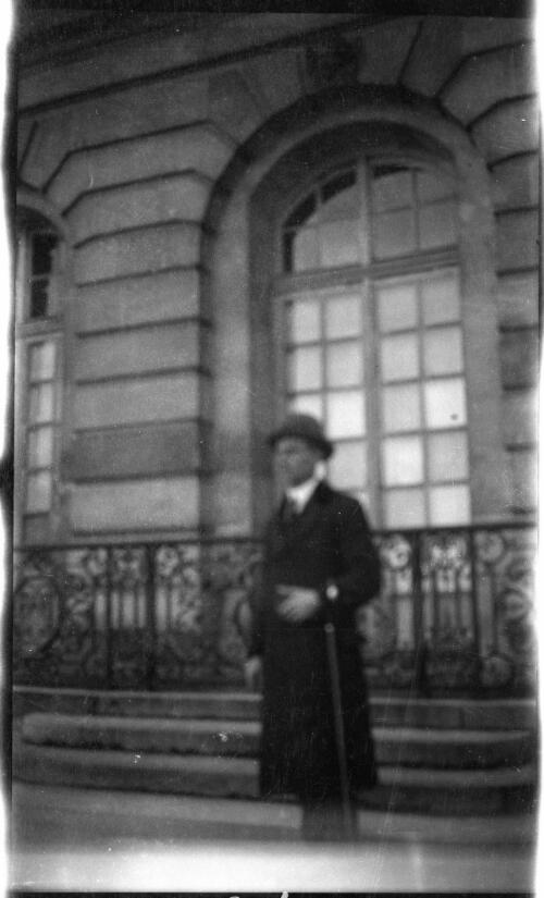 A man with overcoat and hat outside the Hotel de Ville, Châ̂̂lons-en-Champagne, France, ca. 1919 [picture]