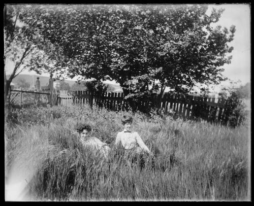Two young women sitting in long grass in a garden, Gundagai, New South Wales [picture] / Charles Gabriel
