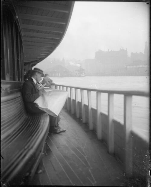 Man reading newspaper on deck of ferry approaching Circular Quay, [N.S.W.], 1906 [picture] / Harold Cazneaux