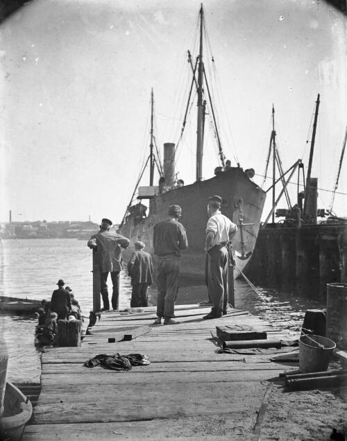 Group of men on wharf, ship berthed, Sydney Harbour [picture] / Harold Cazneaux