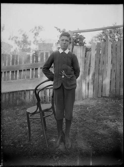 [Boy standing by a chair] [picture] / [William Henry Corkhill]