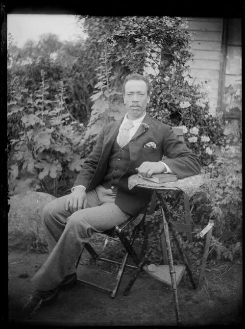 [Man sitting on a chair in a garden] [picture] / [William Henry Corkhill]