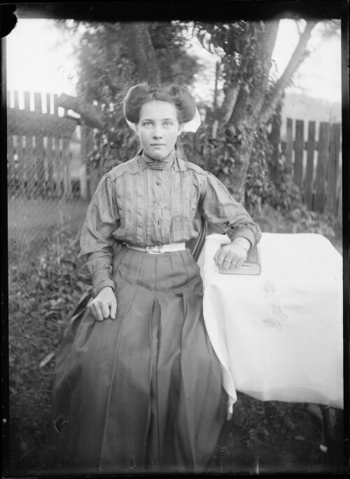 [Young woman sitting by a table] [picture] / [William Henry Corkhill]