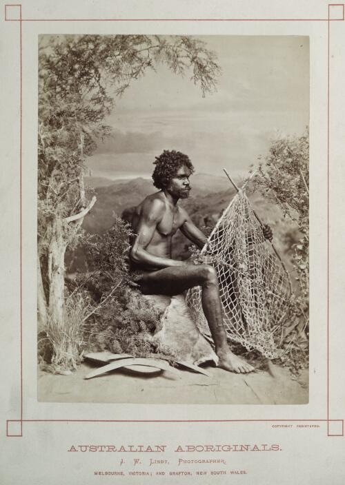 Studio portrait of an Aboriginal Australian man holding a net with boomerangs and a shield at his feet, ca. 1875 [picture] / J.W. Lindt