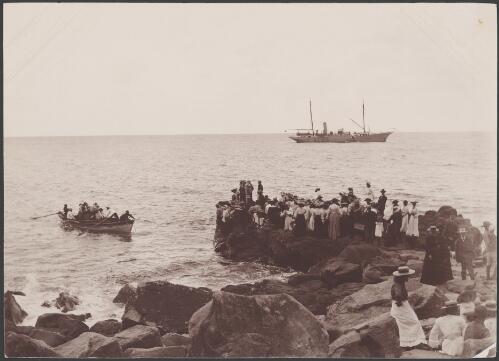 Crowd on shore watching Southern Cross and dinghy off the Cascades, Norfolk Island, 1906 / J.W. Beattie