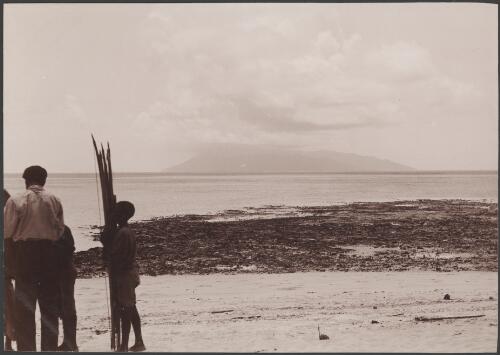 Man and two boys on beach at Rowa with Ureparapara in background, Banks Islands, 1906 / J.W. Beattie