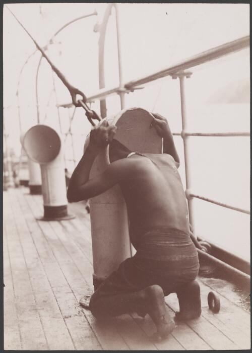 A Melanesian boy looking down the cabin ventilator on the Southern Cross, 1906 / J.W. Beattie