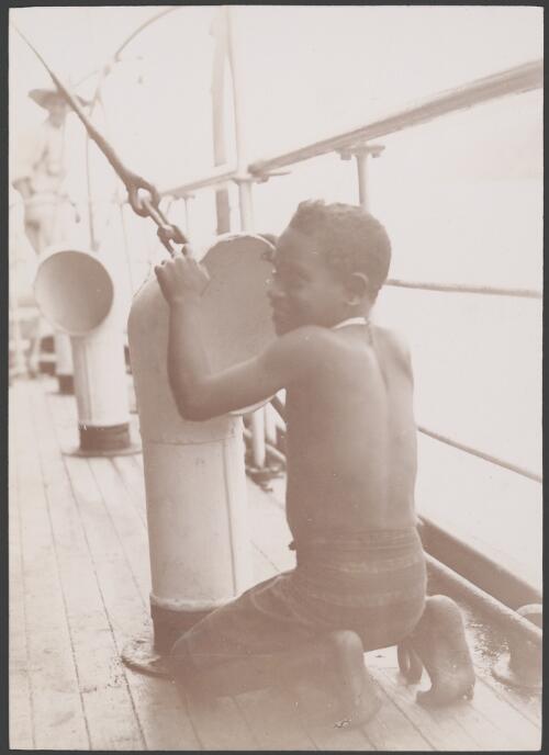 A Melanesian boy kneeling near the cabin ventilator on the Southern Cross, 1906 / J.W. Beattie