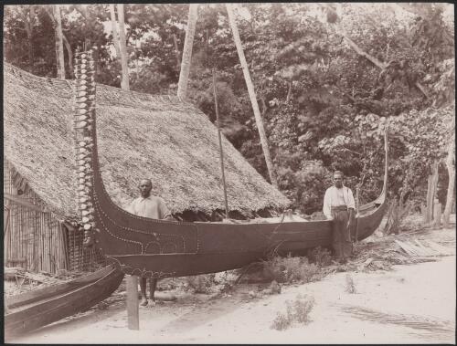Two men standing next to a canoe on a Florida beach, Solomon Islands, 1906 / J.W. Beattie