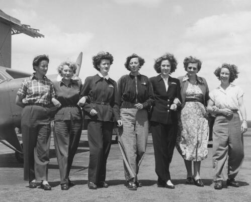 Australian Women Pilots' Association Air Reliability Trial New South Wales entrants Dr. Dorothy Rutherford, Margaret Sincotts, Meg Cornwell, Alix Newbigin, Jacqueline Smith, Marie Richardson and Senja Havard (from left) stand in front of an Auster monoplane on the tarmac at an airfield, 1953 [picture] / Australian News and Information Bureau