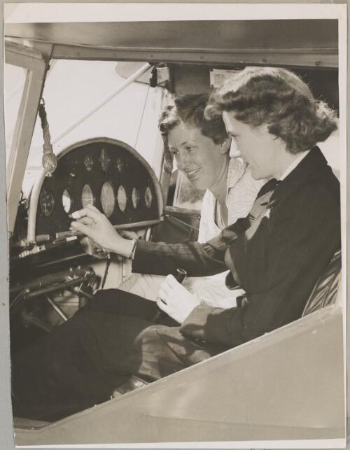 Australian Women Pilots' Association scholarship entrant Margaret Pines (left) is shown flight controls in the cockpit of an Auster J/4 Archer monoplane by pilot Jacqueline Smith at an airfield, New South Wales, November 1952 [picture]