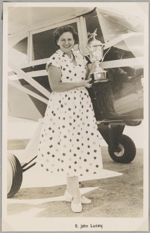 Mabel Glass holding the President's Cup of the Zululand Flying Club in front of a monoplane, South Africa, ca. 1953 [picture]