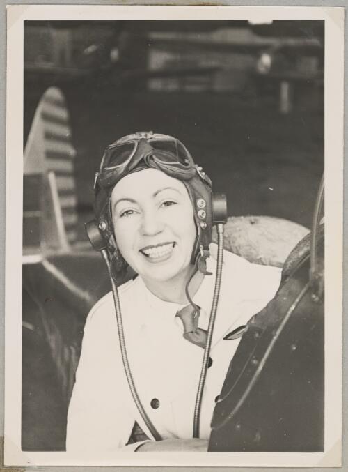 Portrait of Australian Women Pilots' Association member Nancy Leebold (nee Ellis) wearing flying suit in the cockpit of a biplane, May 1954 [picture]