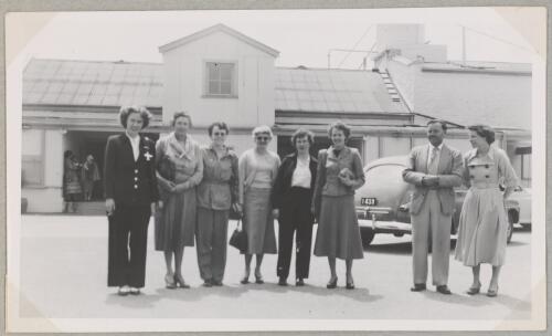 Australian Women Pilots' Association member Jacqueline Smith (far left) with seven unidentified persons standing in car park in front of building for an annual meeting, Adelaide, 1953 [picture]