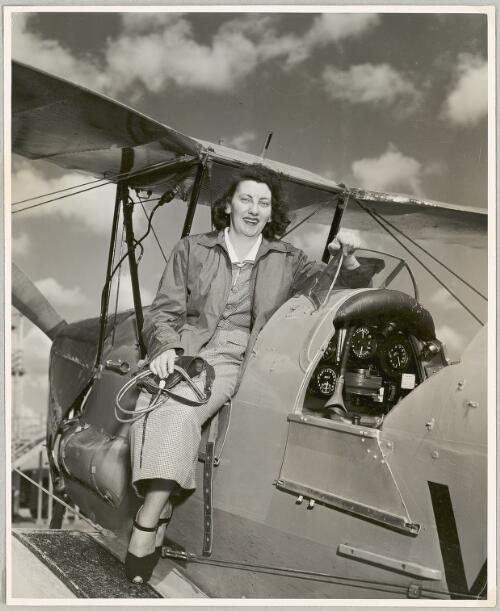 Dawn O'Mara sitting on the edge of the front cockpit of a de Havilland DH82 Tiger Moth biplane, ca. 1953 [picture]